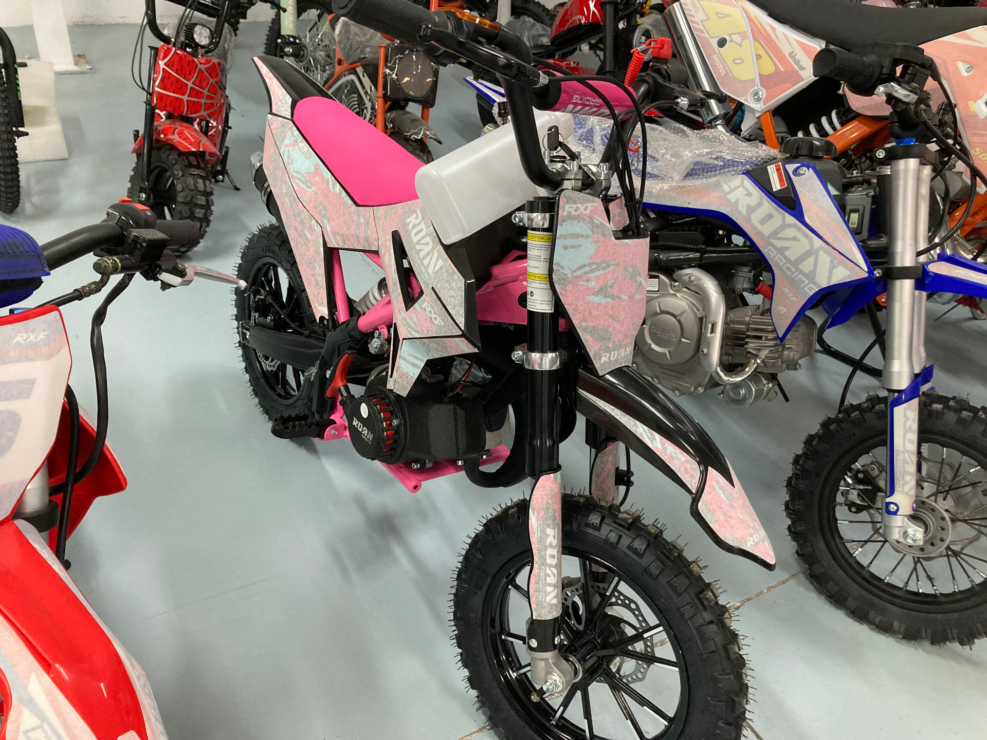 Minicross infantil rosa con gráficos en blanco y celeste