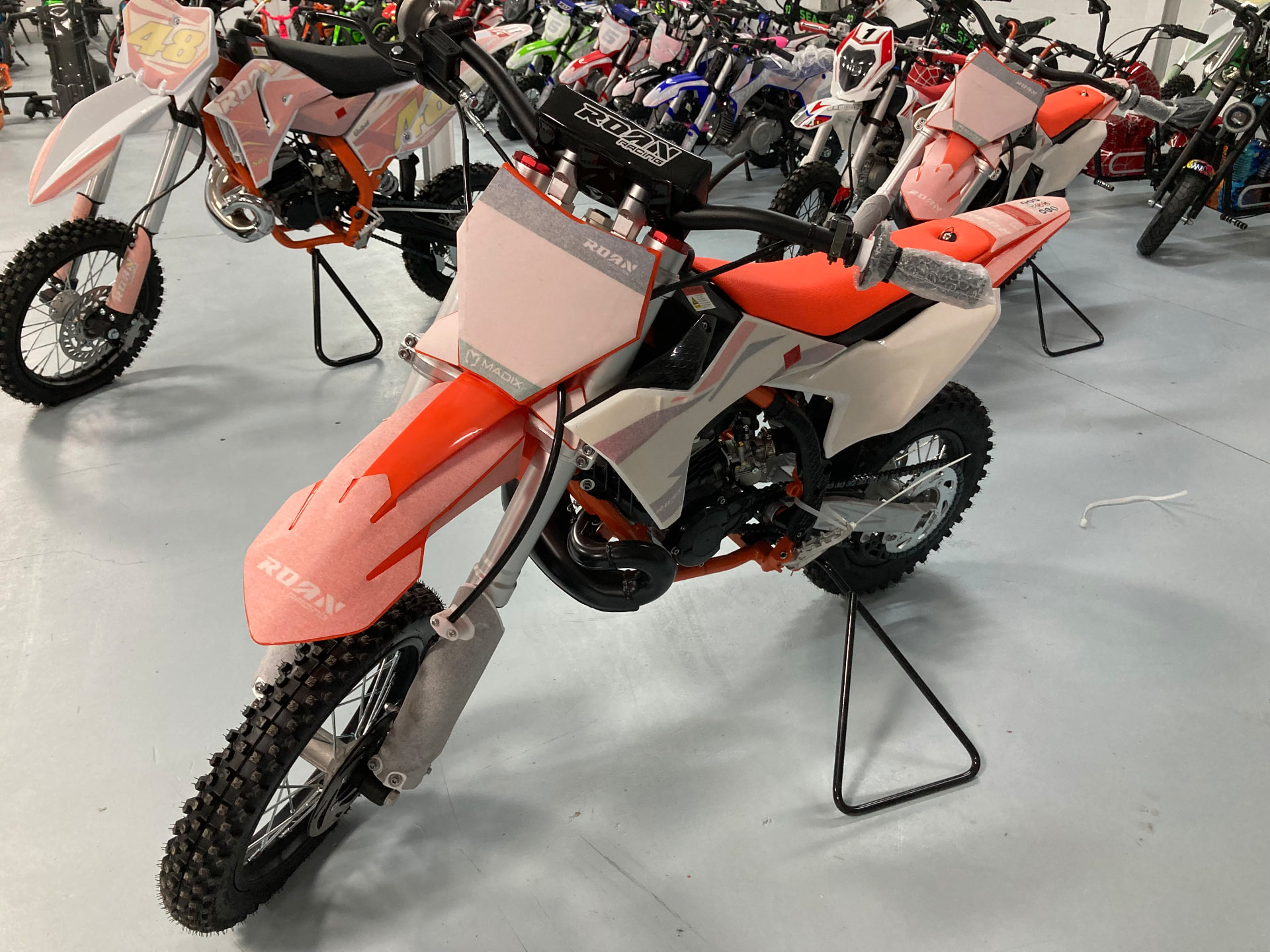 Minicross naranja y blanca sobre caballete en la exposición