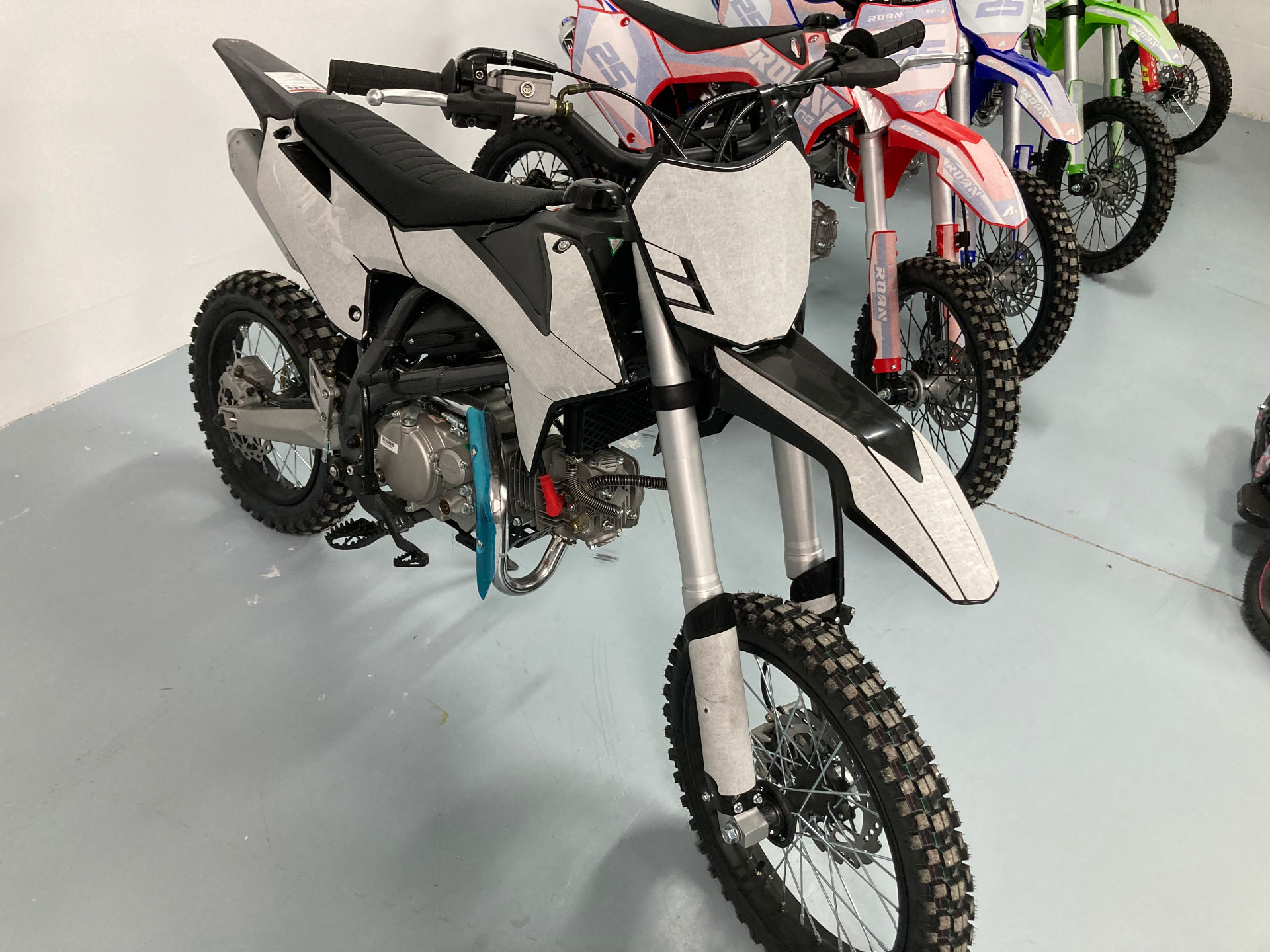 Moto de cross en blanco y negro junto a la fila de motos de la tienda